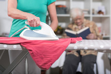 Home Helper Ironing Clothes For An Old Woman