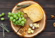 Cheese platter, gouda herb on natural wood disc with grapes and nuts