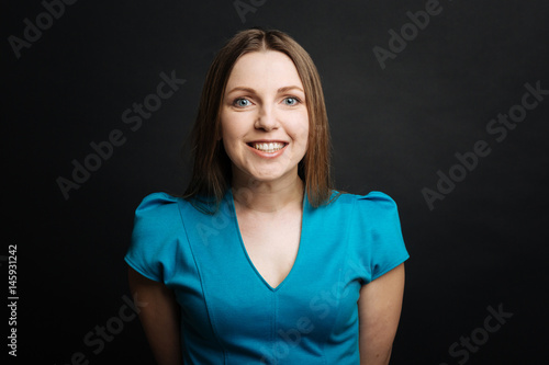 Fotografia Cheerful young woman smiling in the black colored studio