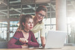 © foxyburrow - Teamwork. Two young businesswomen are working in office. Woman in glasses typing on laptop, second looks at screen.