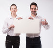 © yanushkov - Young happy couple showing presentation pointing on placard over gray background