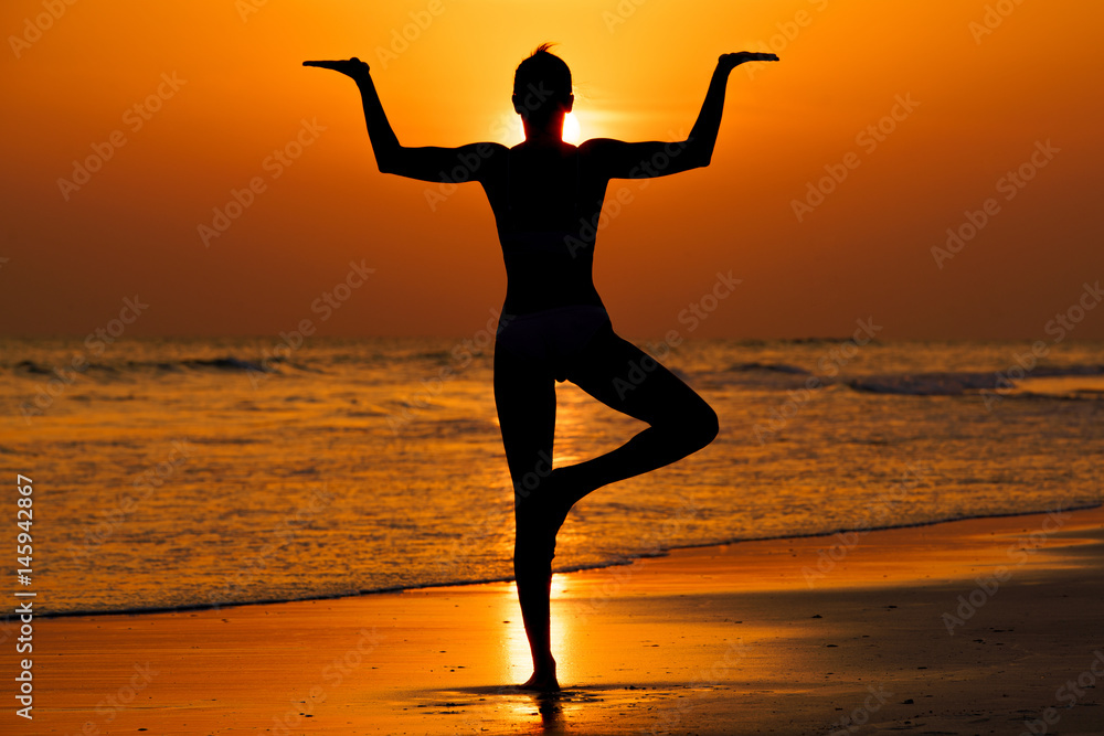 Kobieta ćwicząca jogę na plaży przy zachodzie słońca - obrazy, fototapety, plakaty 