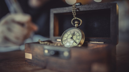 Vintage clock necklace on wooden texture background.