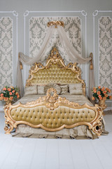 Wall Mural - Luxury bedroom in light colors with golden furniture details. Big comfortable double royal bed in elegant classic interior