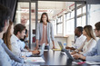 © Monkey Business - Woman addressing team leans on desk at business meeting
