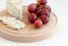     Tasty Sliced Moldy Cheese And Red Grapes On Wooden Plate 