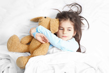 Cute Little Girl Lying In Bed With Cuddly Toy
