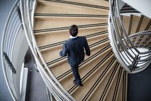 Businessman Walking Up Spiral Staircase In Office