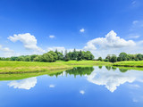 Fototapeta Natura - green grass and pond under the blue sky