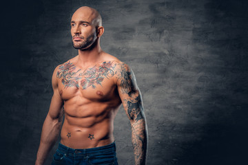 Wall Mural - Shaved head, muscular male with tattoos on his torso over grey vignette background.