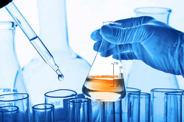 Wall Mural - flask in scientist hand with lab glassware background