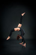beautiful flexible woman doing acrobatic elements on black background