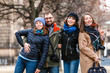 © EdNurg - A team of four happy friends students hugs and laughs in the park of a European city in the winter, travel concept