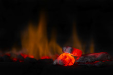 Red Hot Coal Nugget In Focus On Dark Background With Flames. Background Of Raw Coals With Soft Focus Exclusion With Color And Temperature.