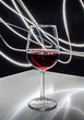 Kieliszek czerwonego wina na białym stole z refleksami świetlnymi w tle 