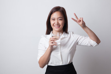 Young Asian woman show victory sign with a glass of drinking water.