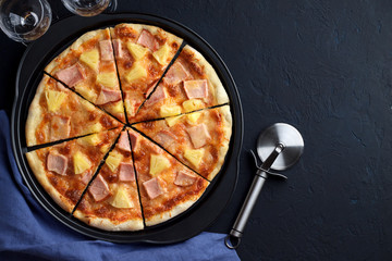 Wall Mural - Homemade pizza hawaii with pineapple and ham on dark stone background.