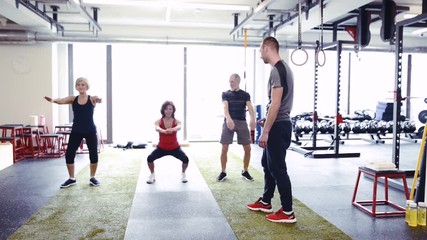 Wall Mural - Fit seniors in gym with their trainer doing squats