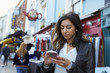 © Guerilla - Young woman using phone in Portobello Road market, close up