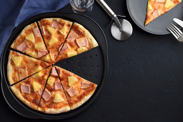 Wall Mural - Homemade fastfood: sliced pizza with pineapple and ham on dark background.