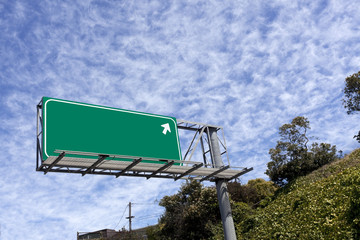Wall Mural - Blank green highway sign with arrow pointing off into buttermilk sky. Copy space.