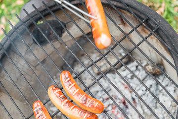 Grillrost mit Würstchen auf einem alten Feuertopf mit brennendem Feuer