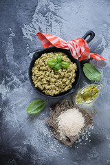 Wall Mural - Above view of risotto with spinach in a frying pan and cooking components, dark grey stone background