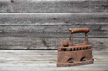 The Heavy And Rusty Old Coal Iron Lies On A Wooden Surface
