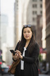 © Erik Isakson/Blend Images - Chinese businesswoman texting on cell phone in city