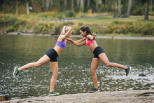 Women Stretching Legs Near Lake