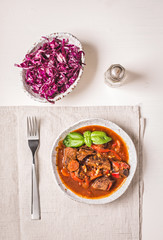 Wall Mural - Bowl of stewed beef and cabbage  on light background top view