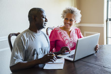 Black Couple Using Laptop At Table