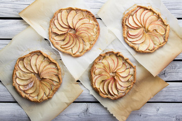 Apple pie on the thin crust with sugar and cinnamon. Apple tart with ricotta cheese and cinnamon. Round pies on the white wooden background. Apple's slices. Piece of pie.