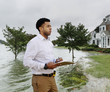 © Roberto Westbrook/Blend Images - Black insurance adjuster examining flooding damage to house
