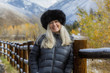 © Steve Smith/Blend Images - Caucasian woman wearing fur hat leaning on wooden fence in winter