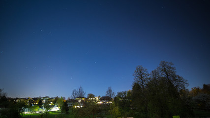 Wall Mural - blue dark night sky with many stars above house and trees.