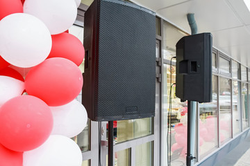 Black loudspeakers hang outside a shop