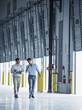 © Erik Isakson/Blend Images - Businessmen walking with clipboard near open loading dock doors