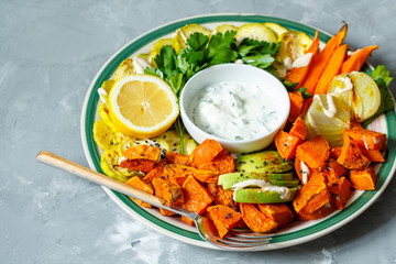 Sticker - Baked sweet potato, zucchini and carrots with sour cream sauce on a plate.