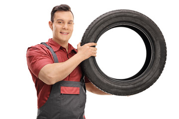 Wall Mural - Young mechanic with a tire looking at the camera