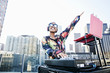 © Peathegee Inc/Blend Images - Female DJ with headphones enjoying music on rooftop party