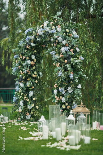 Decorative Lanterns And Vases With Candles Stand Before Green