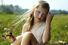 Caucasian Girl Holding Flowers In Windy Field