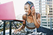 © Peathegee Inc/Blend Images - Female DJ with headphones enjoying music on rooftop party