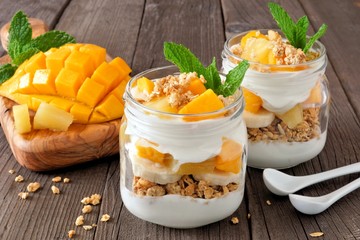 Wall Mural - mango and pineapple parfaits in mason jars, scene on a rustic wood background