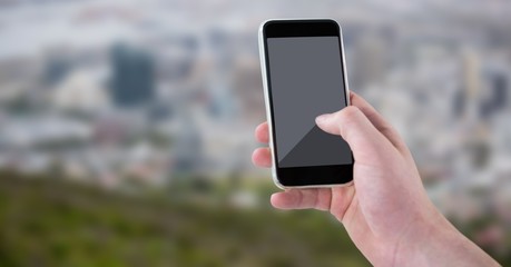 Wall Mural - Hand with phone against blurry skyline