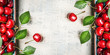 Red sweet cherries background with green leaves on white wooden vintage background, top view, frame