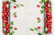 Organic Sweet cherries with leaves , harvest from garden on white rustic wooden  background , top view, frame