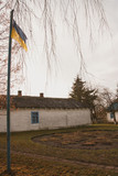 Fototapeta Na sufit - National flag and old-fashioned vintage white one roomed schoolhouse in Ukraine