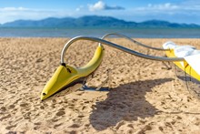 A Yellow Fiberglass Outrigger On A Sandy Beach, With The Sea And Tropical Island In The Background